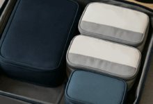 Open suitcase neatly packed with four colorful packing cubes in different sizes, showcasing an organized travel setup on a neutral background.