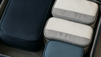 Open suitcase neatly packed with four colorful packing cubes in different sizes, showcasing an organized travel setup on a neutral background.
